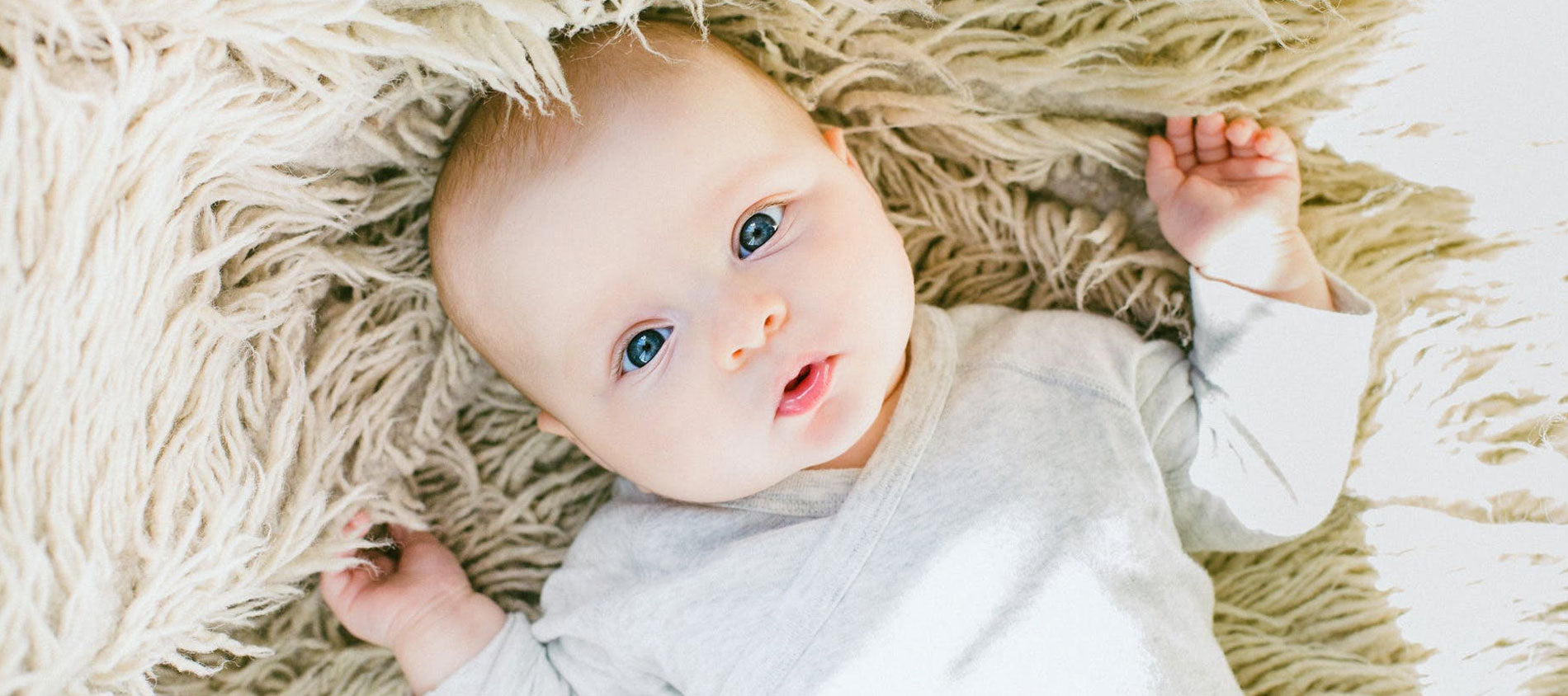baby with big blue eyes on tan rug