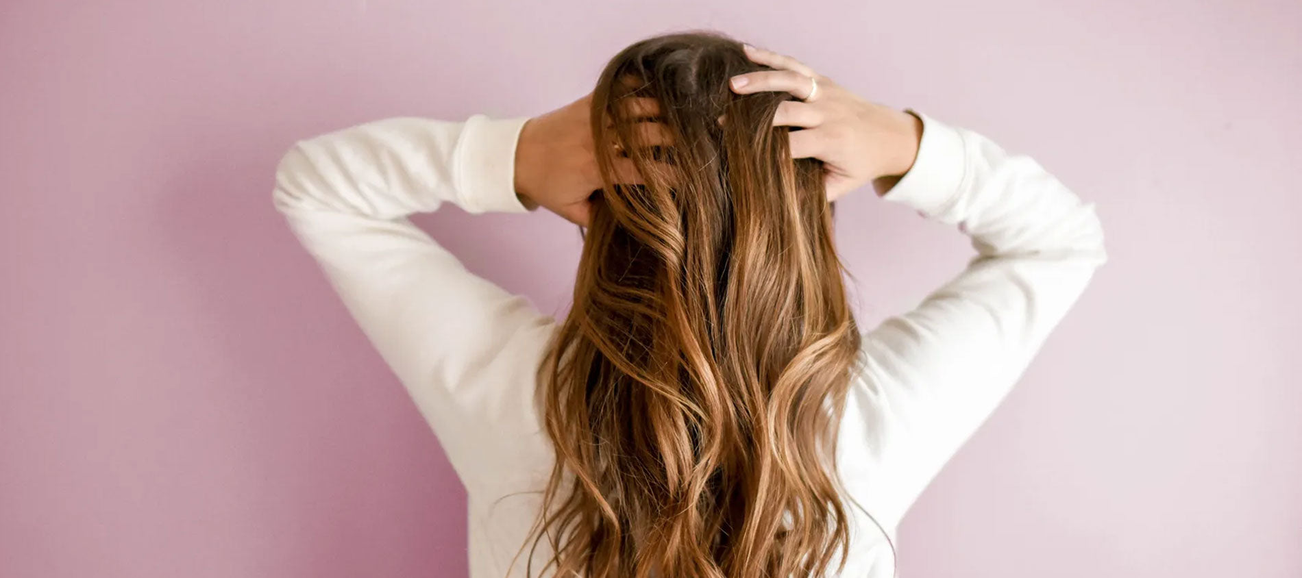 Woman holding hair pink background